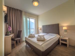 リモーネ・スル・ガルダにあるホテル カポ レモールのベッド、デスク、窓が備わるホテルルームです。