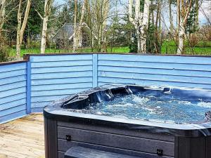 uma banheira de hidromassagem sentada num deque com uma cerca azul em 8 person holiday home in Grevinge em Grevinge