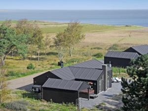 a group of black buildings with the ocean in the background at Four-Bedroom Holiday home in Rømø 5 in Rømø Kirkeby