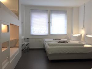two beds in a white room with two windows at Apartment&Rooms near Brandenburg Gate in Berlin