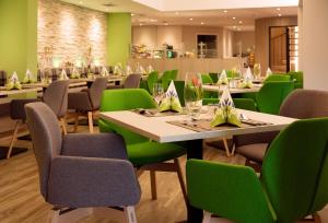 a dining room with tables and green chairs at Thermen-Hotel Rottaler Hof in Bad Füssing