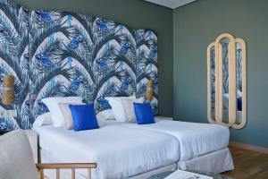 a bedroom with two beds with blue and white pillows at Vincci Selección Posada del Patio in Málaga