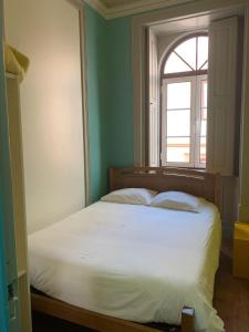 een slaapkamer met een wit bed en een raam bij Meeting Hostel in Figueira da Foz