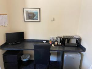 a desk with a microwave and a computer on it at Ivy Cottage-Serviced accommodation in Dyce