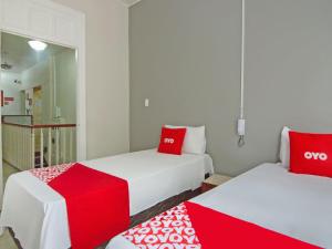 two beds with red and white pillows in a room at OYO Hotel Castro Alves, São Paulo in Sao Paulo