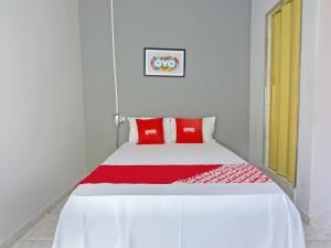 uma cama com almofadas vermelhas num quarto branco em OYO Hotel Castro Alves, São Paulo em São Paulo