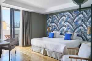 a hotel room with a large bed with blue pillows at Vincci Selección Posada del Patio in Málaga