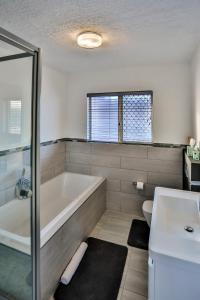 a bathroom with a tub and a toilet and a sink at 302 Kenwyn on Sea- Luxury Beachfront Getaway in Ballito