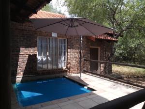 a swimming pool with an umbrella next to a house at Peace@Kruger in Marloth Park