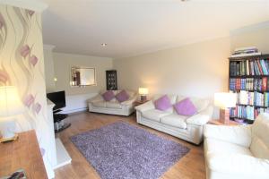 uma sala de estar com 2 sofás brancos e almofadas roxas em Spacious bungalow/private garden-sleeps up to 6 em Marple