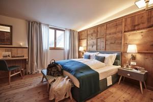 een slaapkamer met een groot bed in een kamer met houten wanden bij Goldene Rose Karthaus a member of Small Luxury Hotels of the World in Senales