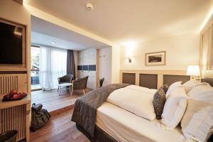 um quarto de hotel com uma cama grande e uma televisão em Goldene Rose Karthaus a member of Small Luxury Hotels of the World em Senales