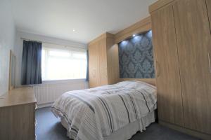 a bedroom with a bed with a wooden headboard and a window at Spacious bungalow/private garden-sleeps up to 6 in Marple