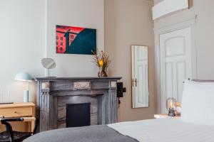 een slaapkamer met een open haard en een schilderij aan de muur bij Maison Haas Hustinx & Spa in Maastricht