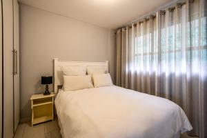 a bedroom with a white bed and a window at Cozumel 320 in Umdloti