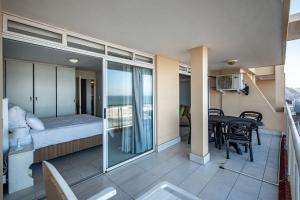 een kamer met een balkon, een bed en een tafel bij Cozumel 320 in Umdloti