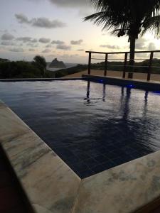 a swimming pool with a gazebo in the background at Pousada Recanto in Fernando de Noronha