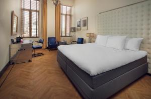 a bedroom with a large white bed and a desk at Hotel New York by WestCord in Rotterdam
