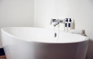 a bathroom with a white tub and a sink at Hotel New York by WestCord in Rotterdam