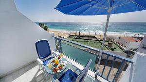 a balcony with a table and an umbrella and the beach at Apartamentos Igramar MorroJable - Adults Only in Morro del Jable