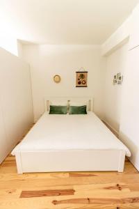 uma grande cama branca num quarto com piso em madeira em Guest H4U - Porto Batalha City Center no Porto