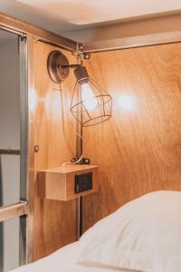 a lamp on a wooden wall next to a bed at Ember Hostel in Denver