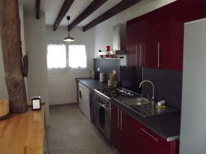 - une cuisine avec des placards rouges, un évier et une cuisinière dans l'établissement Petite maison, à Gabarret