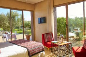 a bedroom with a bed and a chair and a balcony at Villa Jardins D'Isa in Marrakech