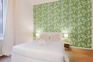ミラノにあるNew & cozy apt in Porta Romanaの緑の壁のベッドルーム1室(白いベッド1台付)