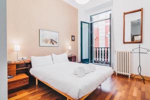 - une chambre avec un grand lit blanc et une fenêtre dans l'établissement Haizean apartment by People Rentals, à Saint-Sébastien