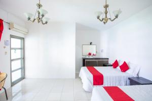 two beds in a white room with red pillows at OYO Hotel Rio in Subteniente López