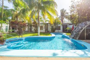 a pool in front of a house with palm trees at OYO Hotel Rio in Subteniente López
