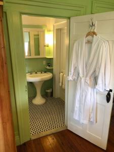 a bathroom with a sink and a robe hanging on a door at Elmwood 1820 Bed & Breakfast Inn in Washington