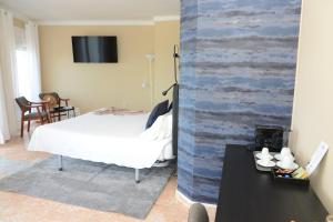 a bedroom with a bed and a wall with a tv at Rallye Hotel in L'Escala