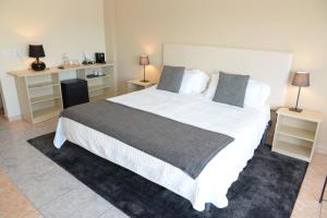 a bedroom with a large white bed and two night stands at Rallye Hotel in L'Escala