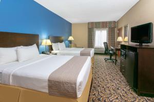 a hotel room with two beds and a flat screen tv at Days Inn by Wyndham Tulsa Central in Tulsa