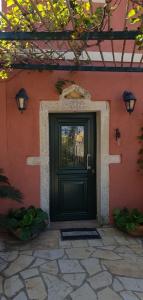 una puerta negra al lado de un edificio rojo en Anemos, en Afionas
