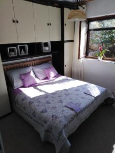 a bedroom with a bed with purple pillows and a window at Apartman Mimi in Klenovica