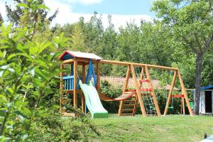 un patio con un parque infantil con tobogán y sillas en Agriturismo La Solagna, en Montebello di Bertona