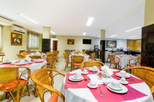 uma sala de jantar com mesas e cadeiras com pratos em OYO Hotel Via Universitária, Anápolis em Anápolis