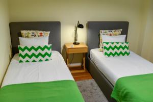 2 camas en una habitación con almohadas verdes y blancas en Lisbon Apartment near Marquês Pombal square, en Lisboa
