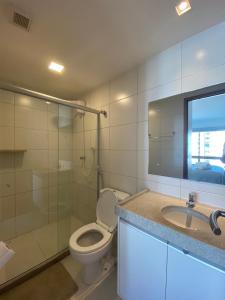a bathroom with a toilet and a sink and a mirror at Apartamento de Luxo em Boa Viagem Perto da Praia. in Recife