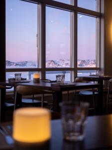 a restaurant with tables and windows with mountains in the background at Hotel Icefiord in Ilulissat