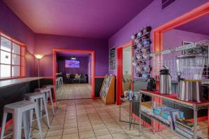 a restaurant with purple walls and stools at Sin City Hostel in Las Vegas