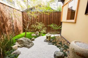Un jardín japonés con un baño para pájaros y una valla. en Rinn Kujofujinoki West, en Kioto
