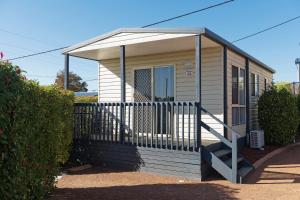 una casa pequeña con porche y puerta en Crestview Tourist Park, en Queanbeyan