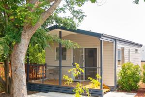 een tiny house met een veranda en een terras bij Crestview Tourist Park in Queanbeyan