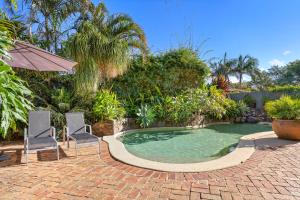 una piscina con 2 sillas y una sombrilla en Florida on Carlyle Street en Byron Bay