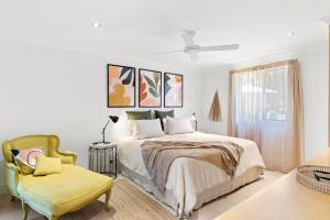 a white bedroom with a bed and a chair at Florida on Carlyle Street in Byron Bay