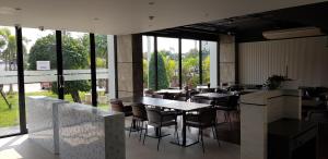 a restaurant with tables and chairs and large windows at KOS Hotel Suvarnabhumi Airport -SHA Extra Plus in Min Buri